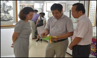 2018年9月13日，学校纪委书记覃宇环（左）和黄鹄副校长参观永利总站ylzz第一届师生书画展。